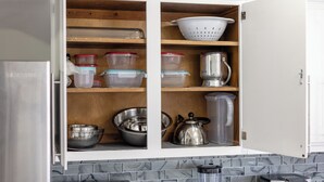 Un meuble de cuisine contenant des boîtes de rangement, une passoire et une bouilloire.