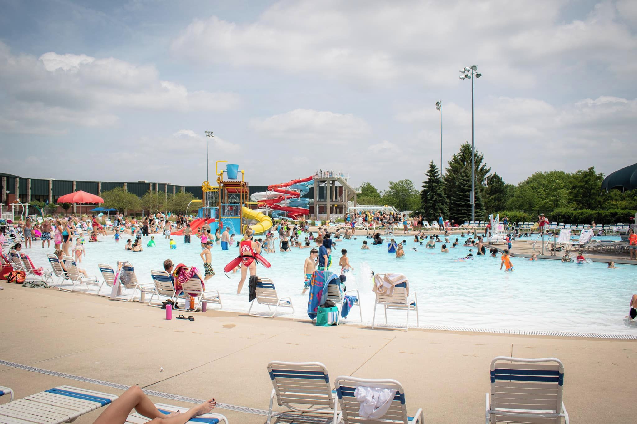 A public swimming pool with multiple water slides and a covered spectator area.