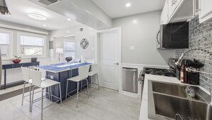 Une cuisine moderne dotée d’un îlot central, de meubles blancs et d’un évier en acier inoxydable.