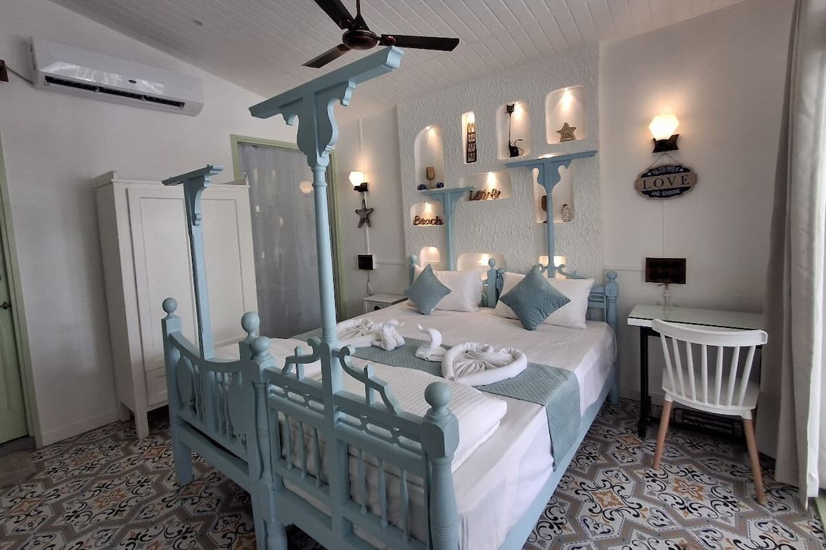 A bedroom with a four-poster bed, a desk, and a chair.