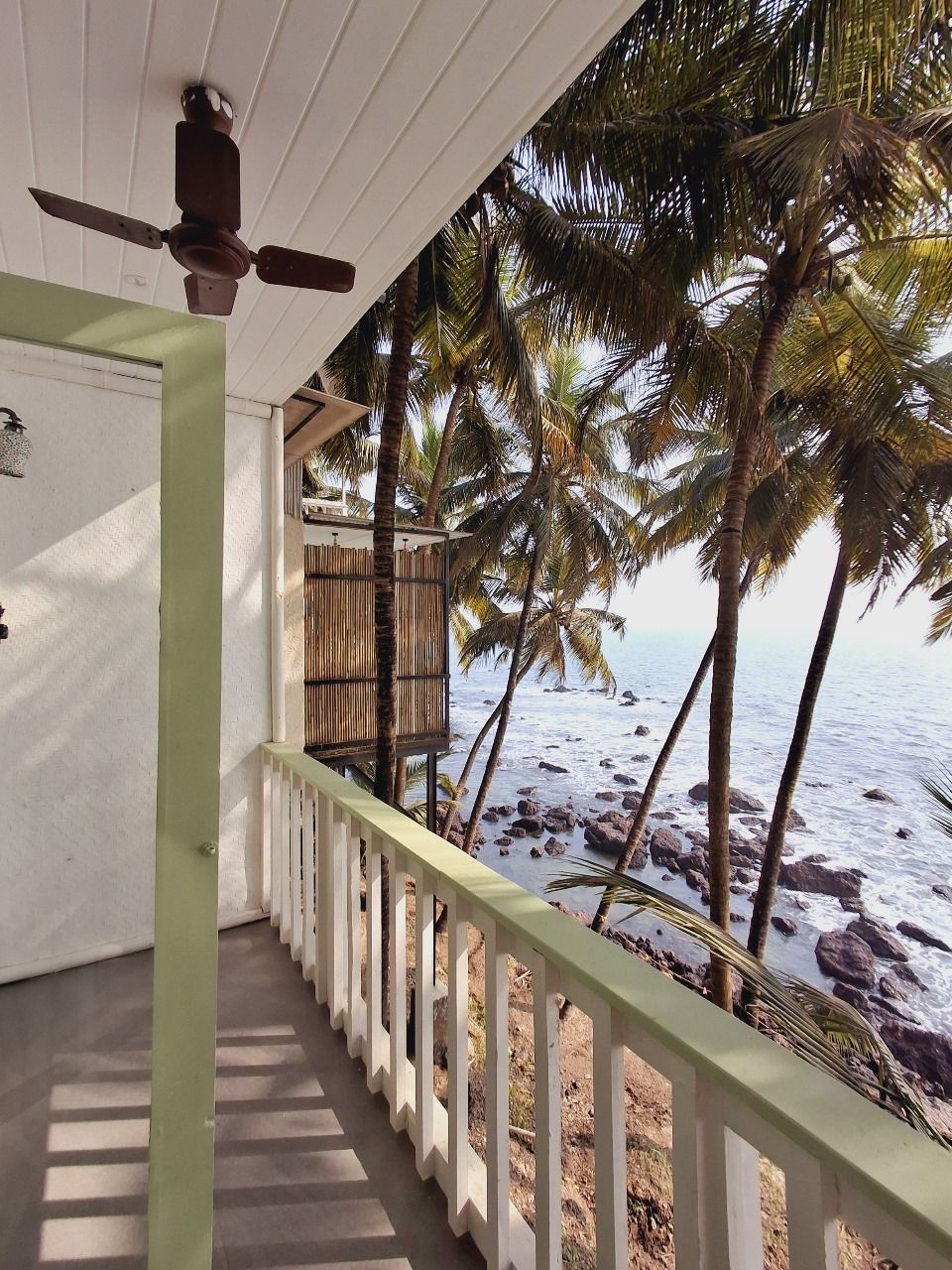 Un balcón con vista a la playa y palmeras.