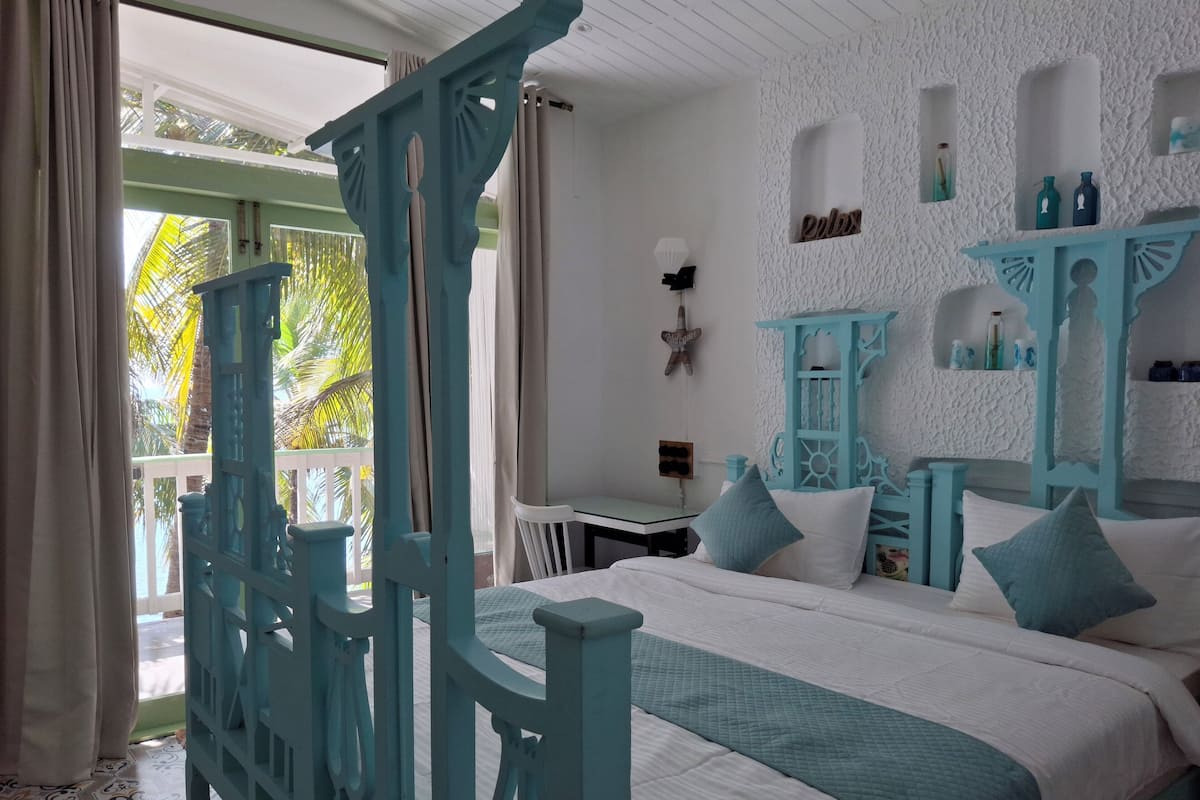 A bedroom with a bed, a nightstand, a dresser, and a window with curtains.