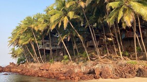 Une plage bordée de palmiers et d’une côte rocheuse.