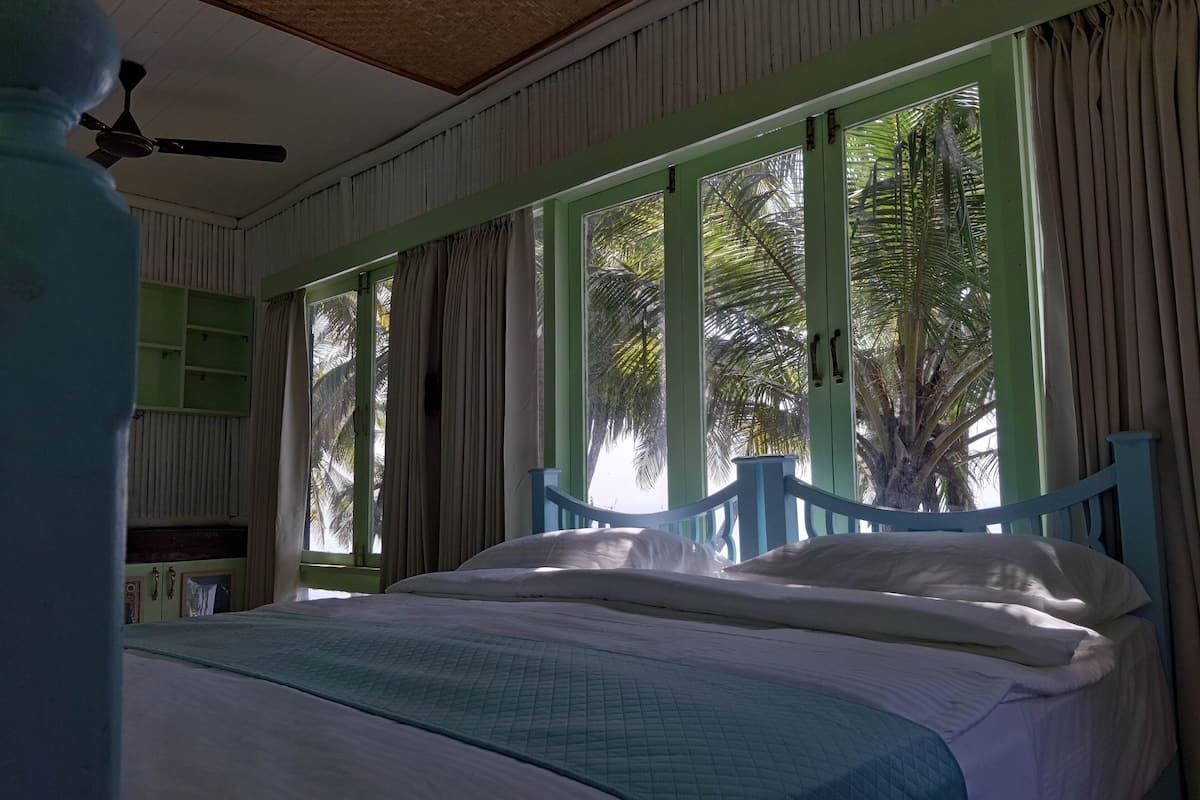 A bedroom with a bed, curtains, and a ceiling fan.