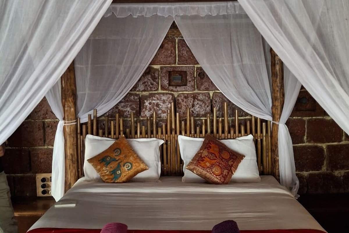 A bed with a canopy, two pillows, and rolled towels.