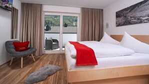 Quarto de hotel com uma cama, uma cadeira, um tapete pequeno e uma porta de vidro deslizante que dá para uma área externa.