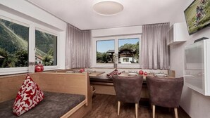 Uma cozinha moderna com área de refeições, grandes janelas com vista para as montanhas e um espaço de estar acolhedor.