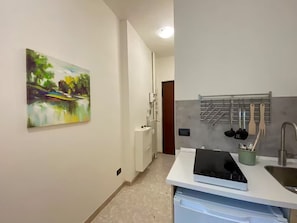 Een koelkast, een kookplaat, kookgerei, borden en bestek, eettafels