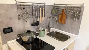 Une cuisine compacte équipée d’une cuisinière intégrée, d’un évier et de supports pour ustensiles fixés au mur.