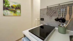 Une cuisine moderne dotée d’une plaque de cuisson à induction noire, d’un porte-ustensiles suspendu et d’un pot à ustensiles vert.