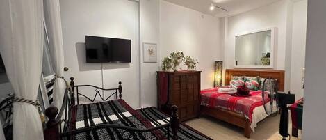 A bedroom with two beds, a TV, a mirror, and a ceiling fan.