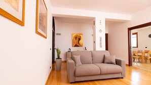 Un salón con un sofá color beige, una planta en maceta y un cuadro en la pared.