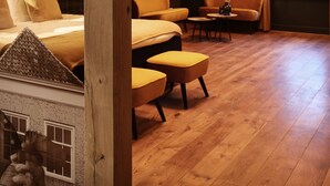 A cozy attic bedroom with wooden beams, a bed, two chairs, a small table, and a window. - Stadshotel Geertruidenberg (Geertruidenberg)