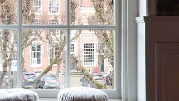 A bedroom with a large window, a bed with white bedding, and two pillows on the windowsill.