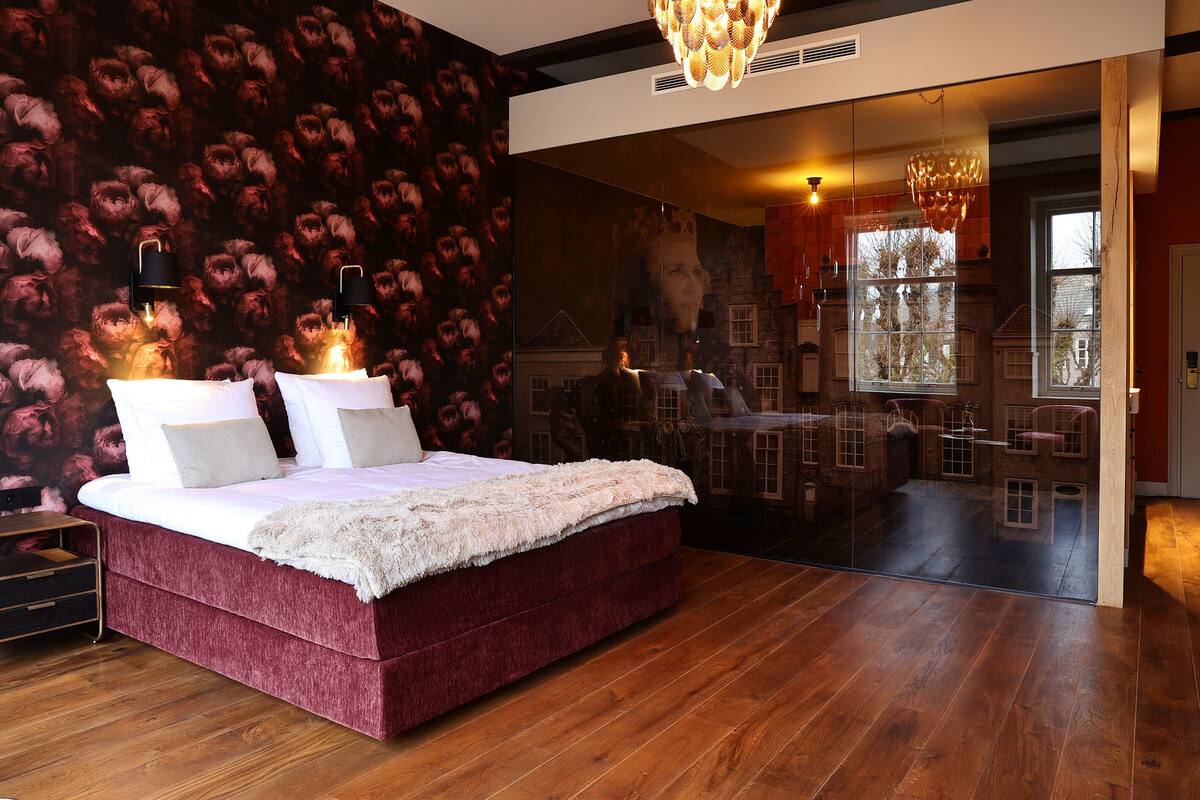 A bedroom with a large bed, a mirror, and a chandelier.