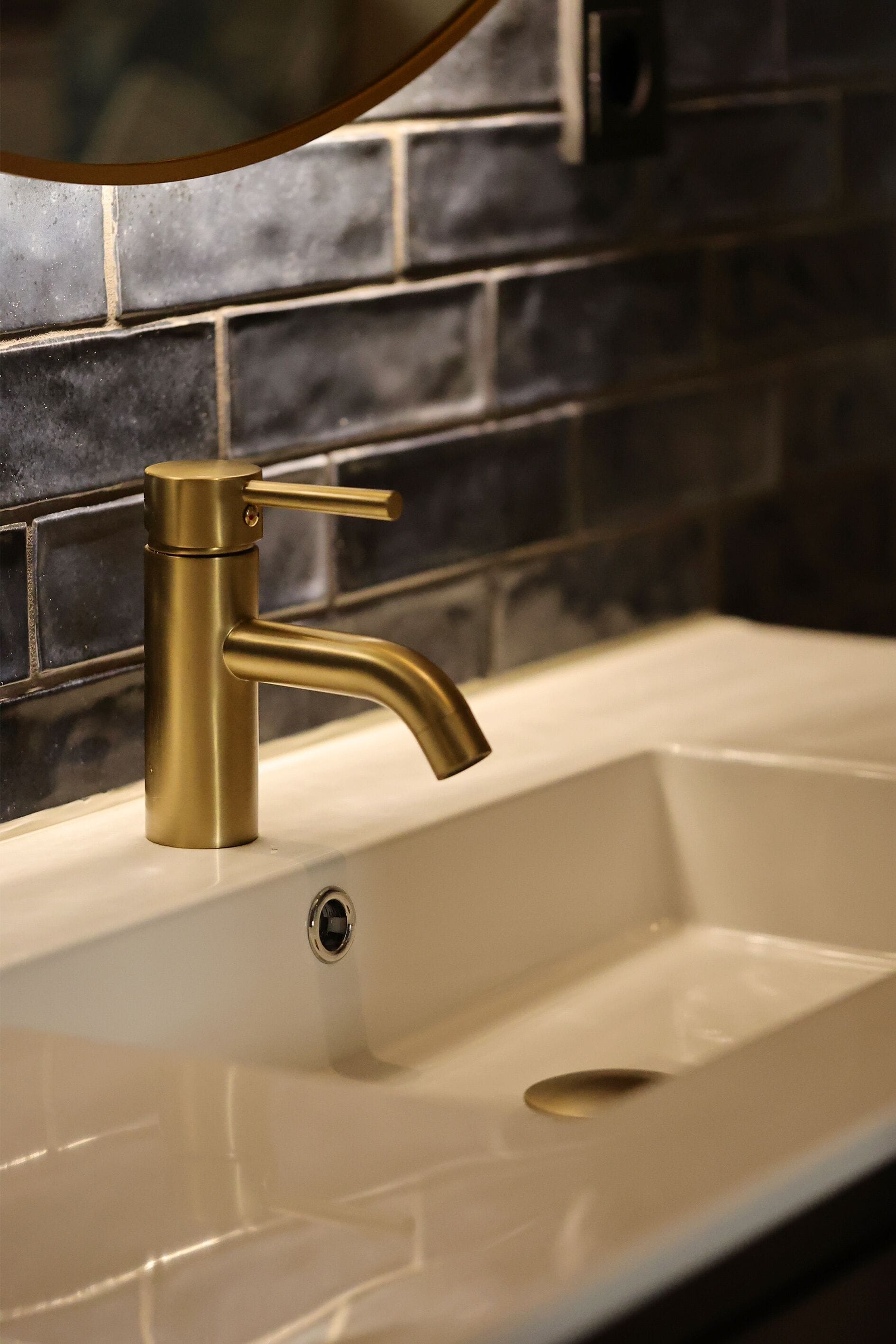 Un lavabo amb un aire de metall daurat i un mirall penjat a sobre.