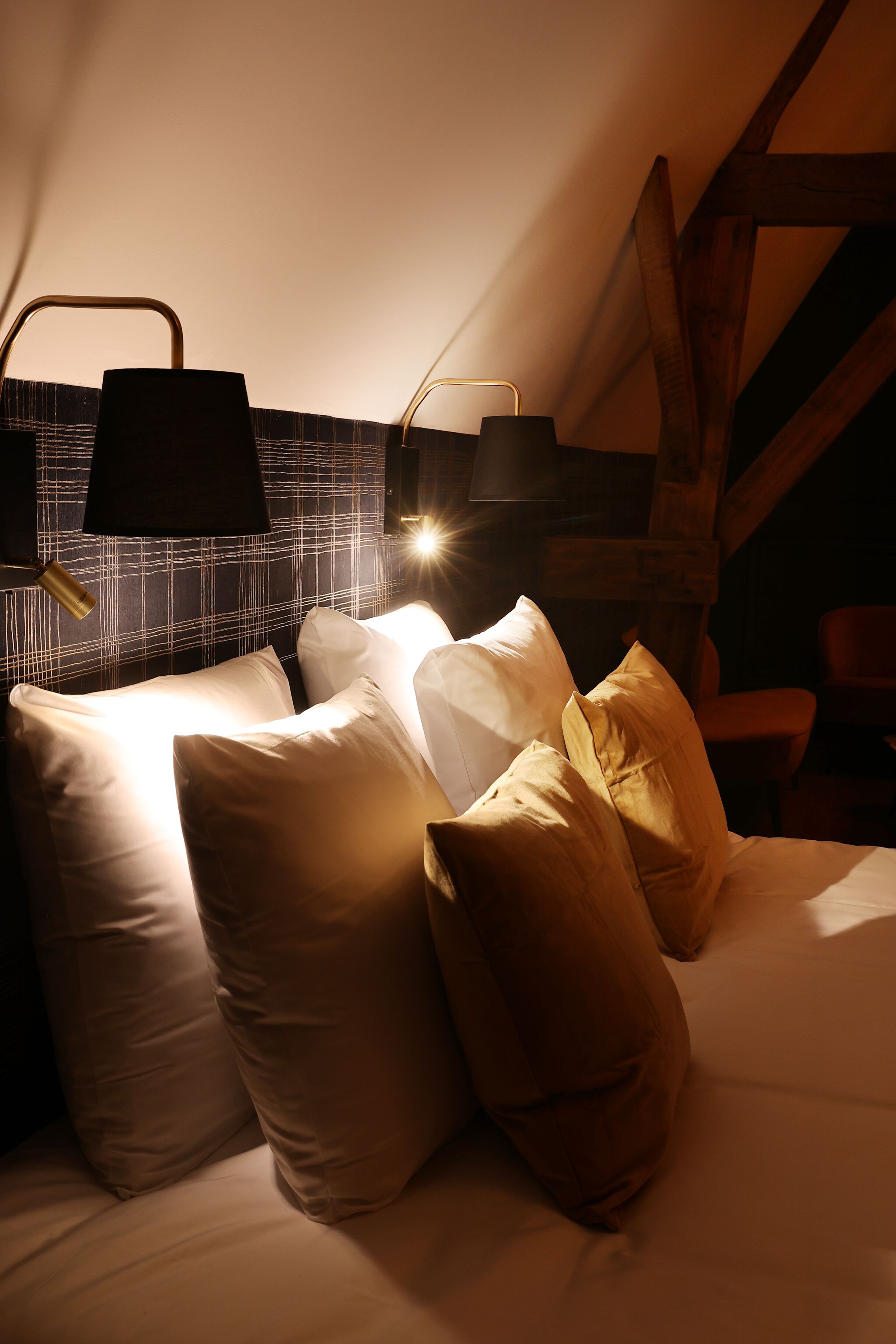 Une chambre confortable avec un lit, des oreillers et une table de chevet avec une lampe.