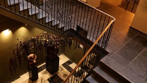 A staircase with a black railing, a chandelier, and a checkered floor. - Stadshotel Geertruidenberg (Geertruidenberg)