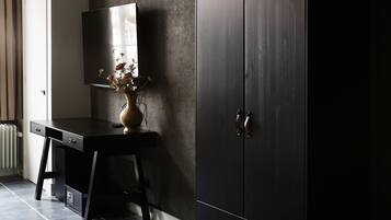 Una habitación con un armario de madera oscura, un escritorio con un florero y un espejo grande.