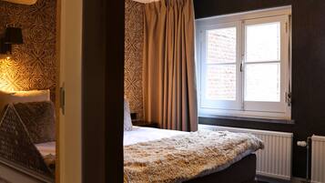 A bedroom with a large bed, a window with curtains, and a radiator.
