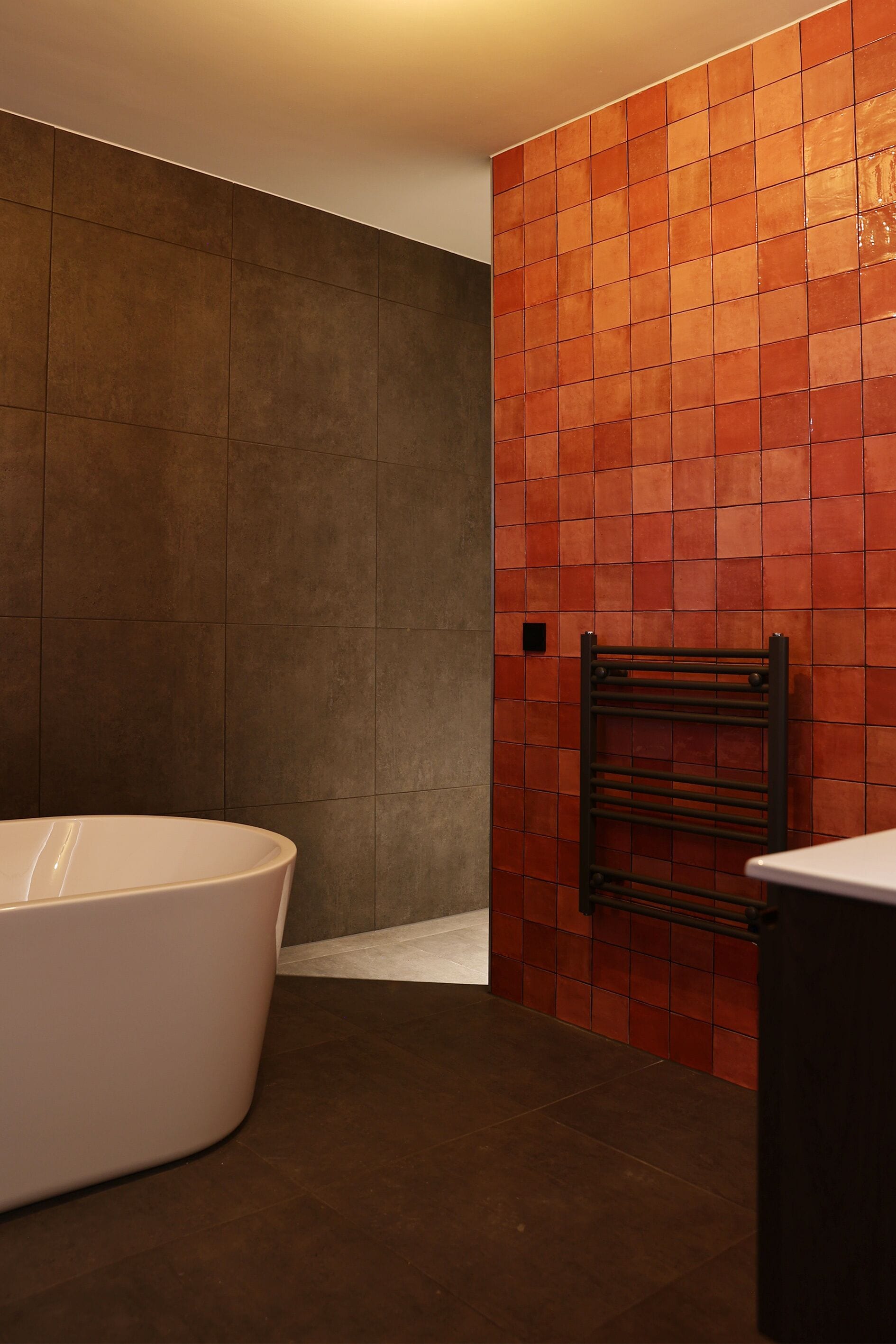 Un baño moderno con una bañera independiente, un perchero y una pared con azulejos.