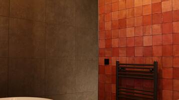 Un baño moderno con una bañera independiente, un perchero y una pared con azulejos.