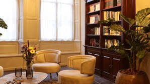 A well-lit room with a chandelier, a large bookshelf, and comfortable seating. - Stadshotel Geertruidenberg (Geertruidenberg)