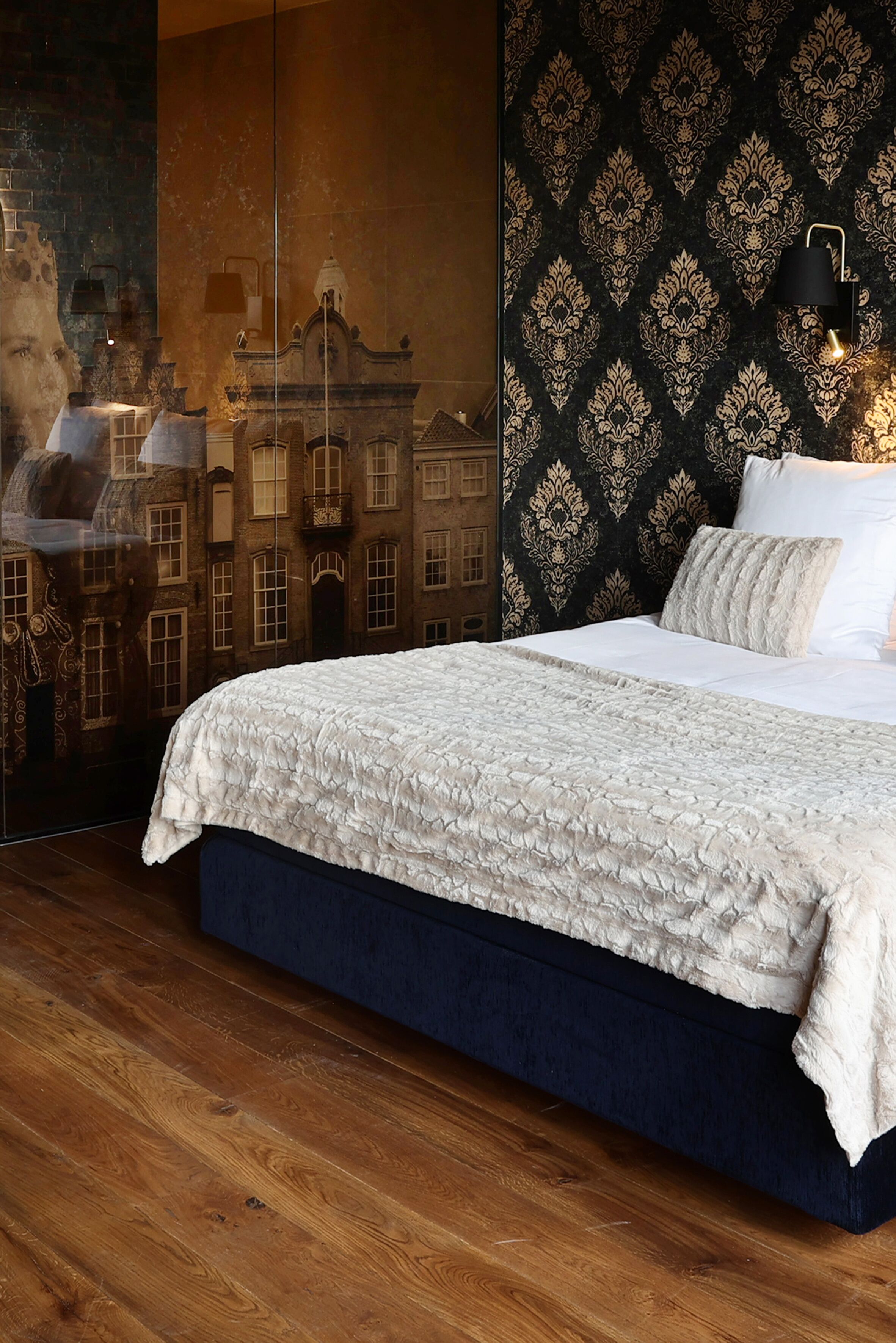 Ein Schlafzimmer mit einem großen Bett, einer dunkelblauen Kopfteil und einer Wand mit Muster.