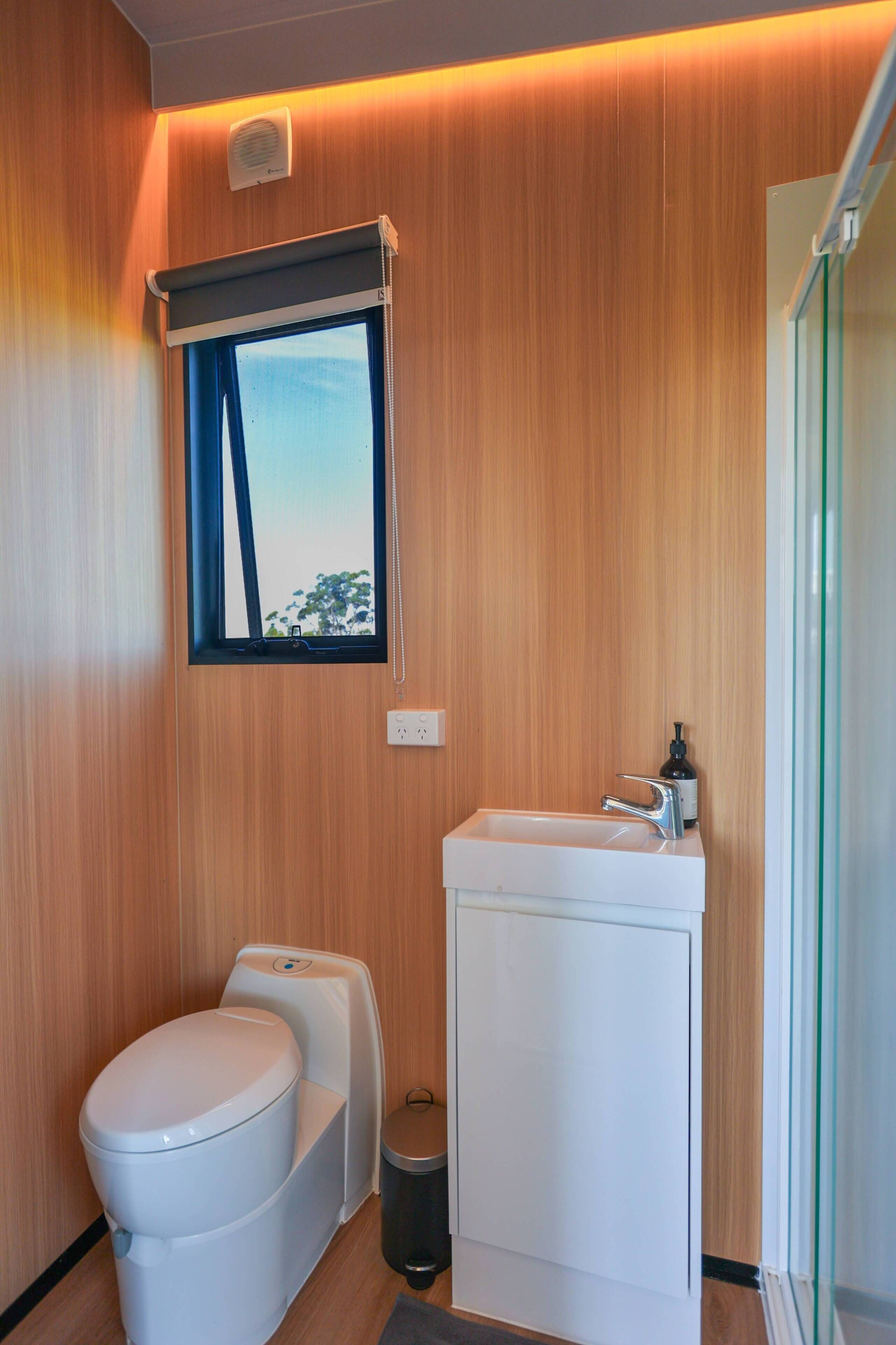 Een moderne badkamer met toilet, hygiëneschuimer en wastafel.