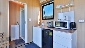 Eine kompakte Küche mit Mikrowelle, Kaffeemaschine und kleinem Kühlschrank.