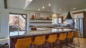 Une cuisine moderne dotée d’un grand îlot central, de tabourets de bar, d’appareils électroménagers en acier inoxydable et d’armoires en bois.