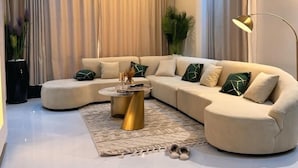 A modern living room with a beige sectional sofa, a round coffee table, and a floor lamp. - Ace Homes Kampala (Kampala)