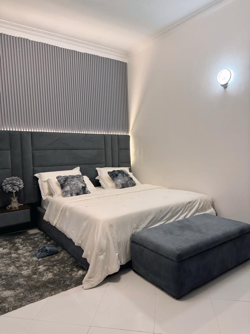 Een moderne slaapkamer met een bed, nachtkastje en een bankje.