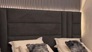 A modern bedroom with a dark headboard, two white pillows, and a gray patterned pillow. - Ace Homes Kampala (Kampala)