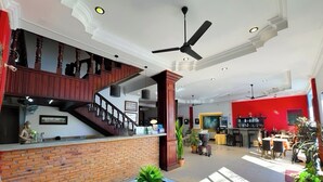 Eine großzügige Lobby mit Treppe, einer Rezeption und einem Essbereich.