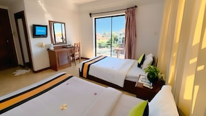 Ein Hotelzimmer mit zwei Betten, einem Schreibtisch, einem Fernseher und einem Balkon mit Blick.