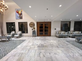 A spacious living area with a large chandelier, a clock, and a wardrobe.