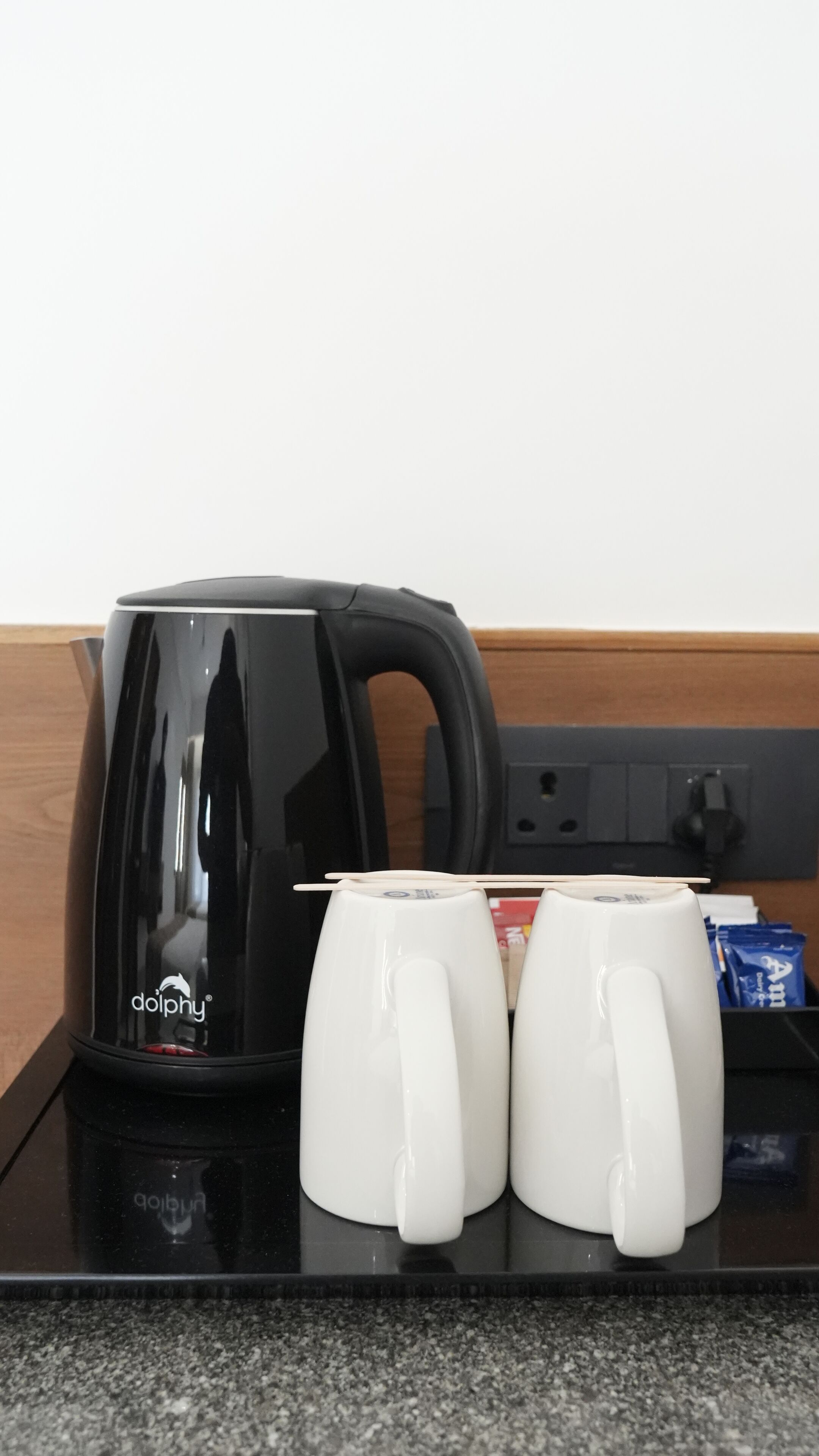 Una moka nera con due tazze bianche su un piano di lavoro.