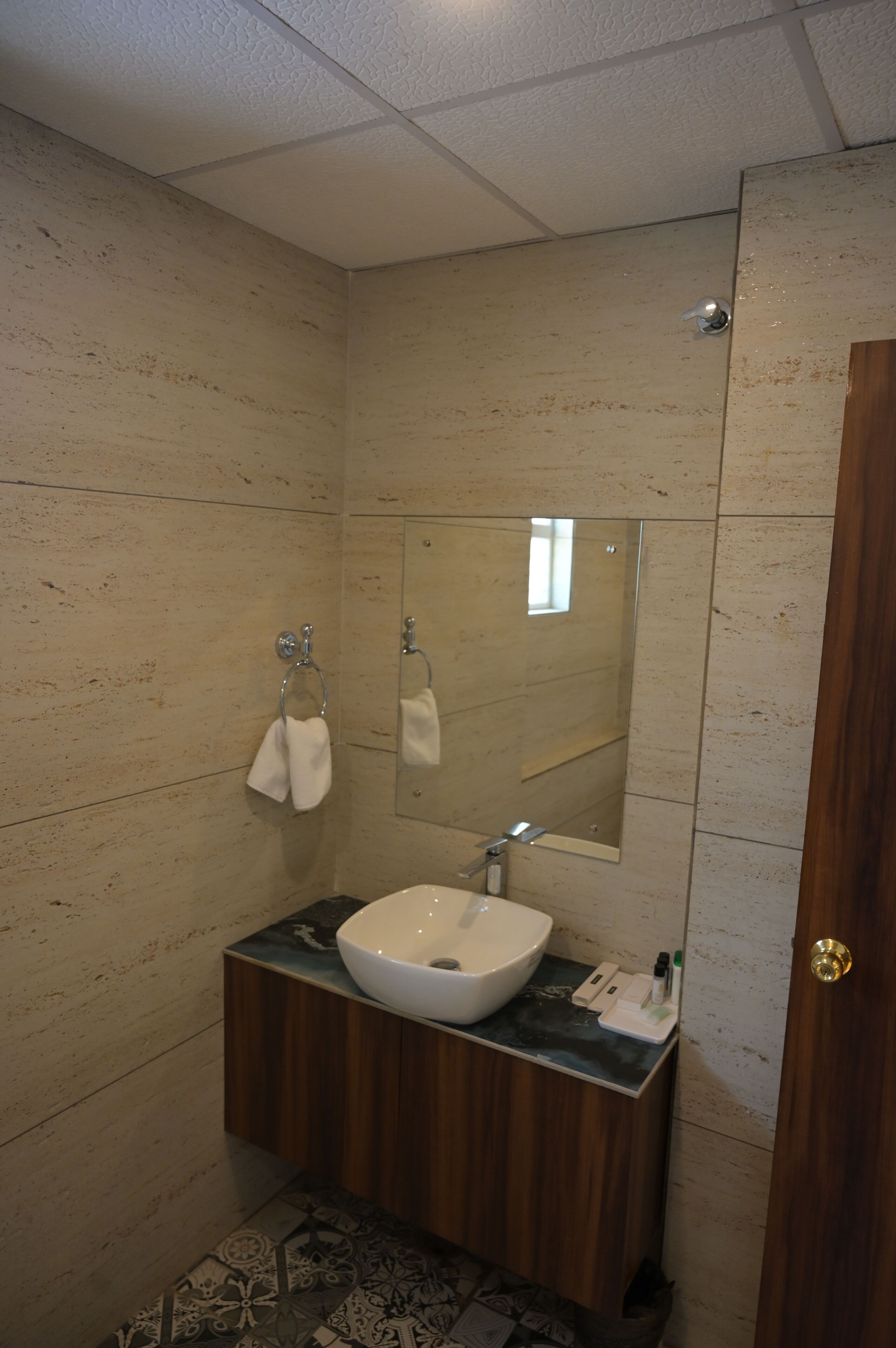 A bathroom with a white sink, wooden vanity, and a mirror.