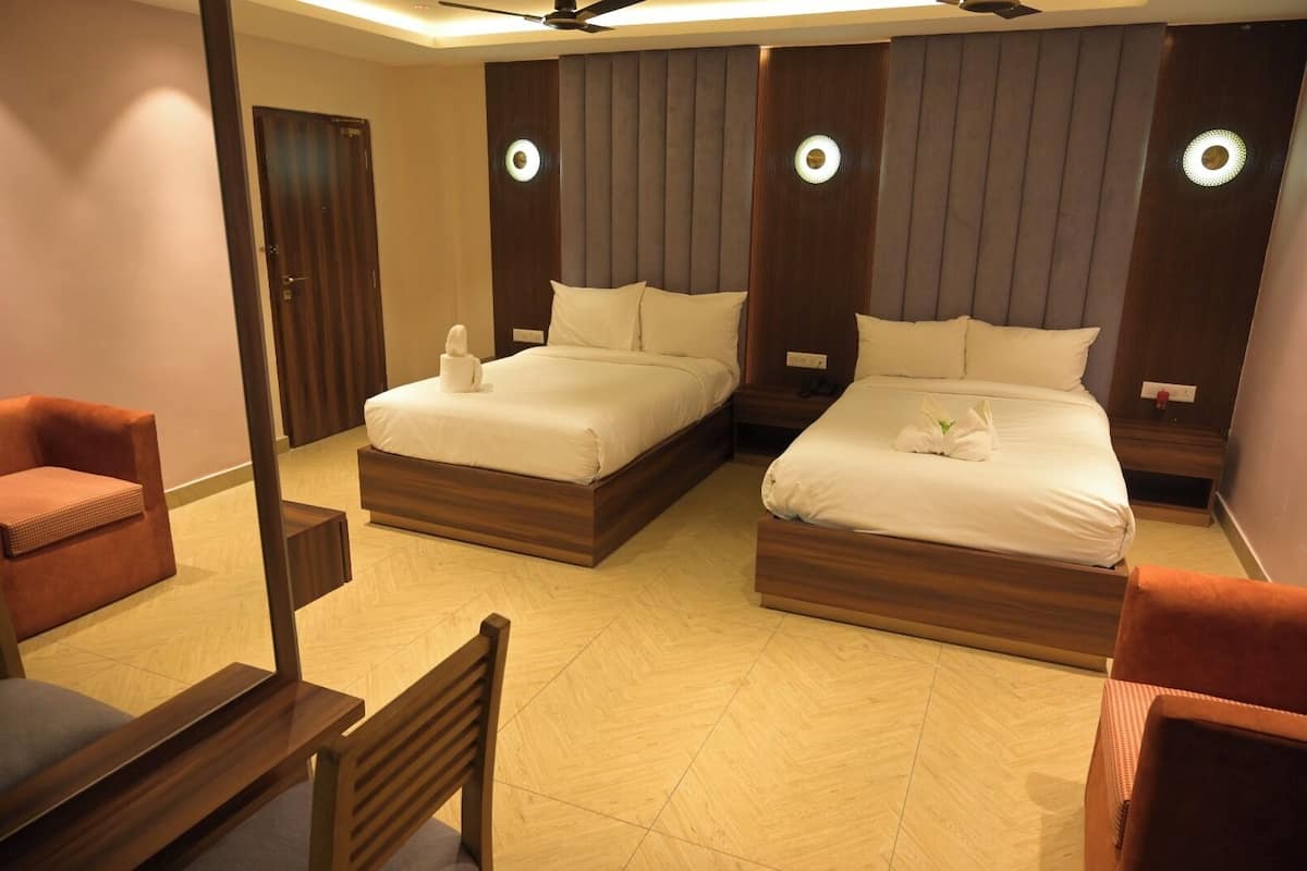 Ein Hotelzimmer mit zwei Betten, Holzboden, einem großen Spiegel und einem Deckenventilator.