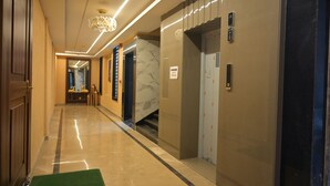 A modern hotel corridor with marble flooring, a green mat at the entrance, and a marble elevator. - Hotel Ananta Sayana  (Bhubaneshwar)
