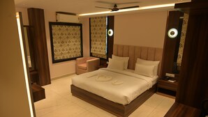 A modern bedroom with a large bed, bedside tables, a chair, and a ceiling fan. - Hotel Ananta Sayana  (Bhubaneshwar)