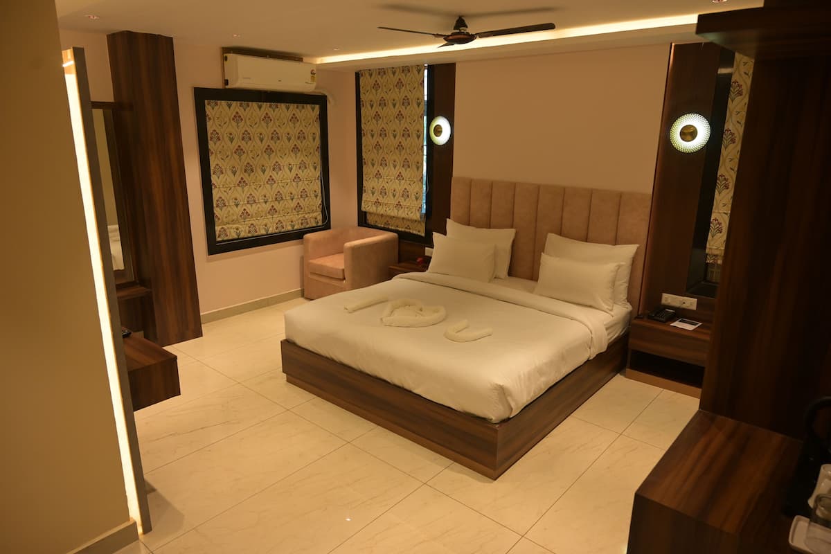 Ein modernes Schlafzimmer mit einem großen Bett, Nachttischen, einem Sessel und einem Deckenventilator.