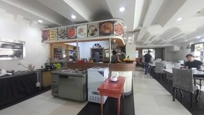 Un restaurante moderno con una barra central, varias zonas de estar y una cocina visible al fondo.