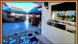 Una habitación con suelo de baldosas, televisión y una mesa de madera con sillas.