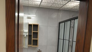 A bathroom with a wooden cabinet, a white toilet, and a glass shower enclosure.