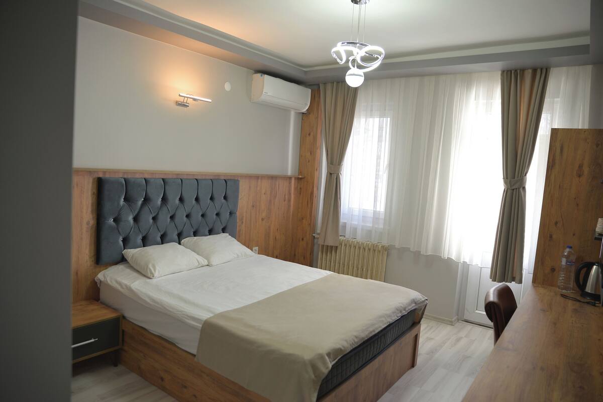 Een slaapkamer met een groot bed, een houten hoofdbord, nachtkastjes en een inbouwkleerkast.