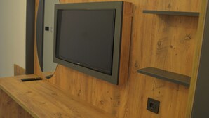 A room with a wooden desk, a mounted flat-screen TV, and a mirror.