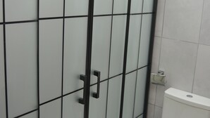 A bathroom with a white toilet and a glass-enclosed shower stall.