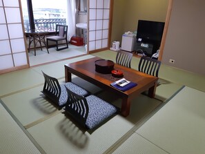 A traditional Japanese-style room with tatami flooring, a wooden dining table with cushions, and a TV. - KKR Enoshima New Koyo (Fujisawa)